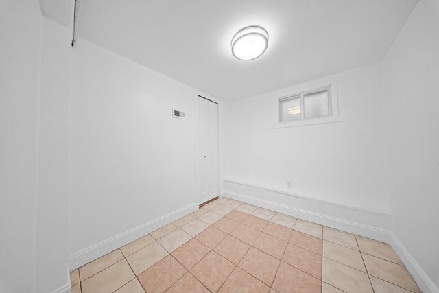 empty room featuring light tile patterned flooring, visible vents, and baseboards