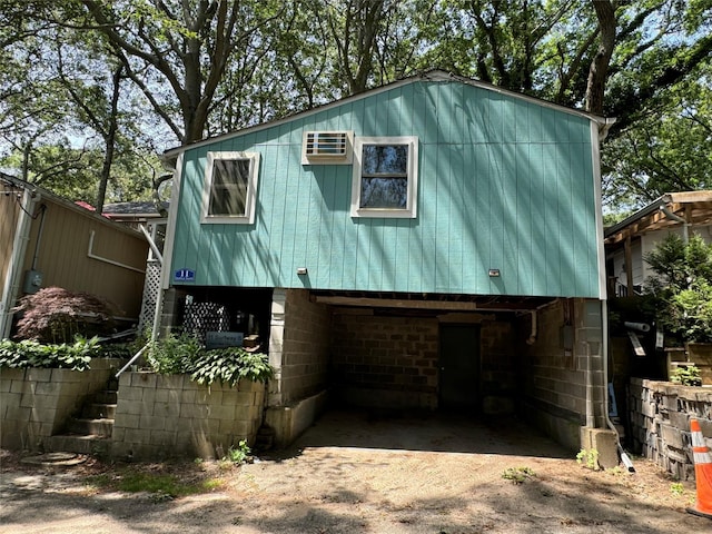 exterior space featuring a carport, a wall mounted air conditioner, and driveway