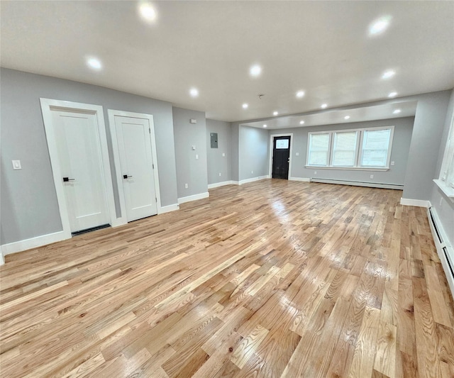 unfurnished living room with light wood-style flooring, a baseboard heating unit, baseboards, and recessed lighting