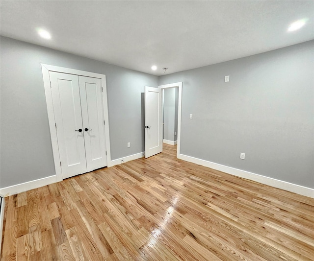 unfurnished bedroom featuring baseboards, a closet, and light wood-style floors