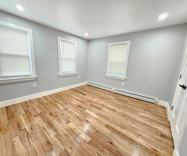 spare room featuring a baseboard heating unit, recessed lighting, light wood-type flooring, and baseboards