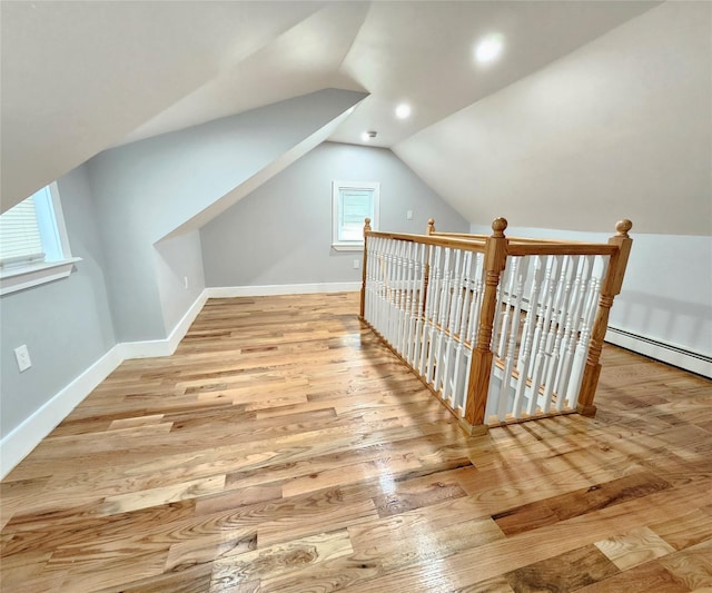 additional living space featuring baseboards, vaulted ceiling, and wood finished floors