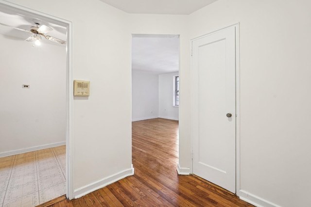 corridor with hardwood / wood-style flooring and baseboards