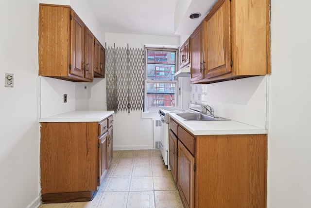 kitchen featuring brown cabinetry, light countertops, a sink, and light floors