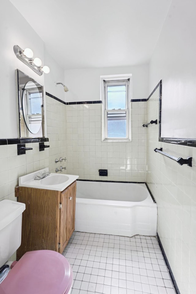 full bath with shower / bathtub combination, tile patterned flooring, toilet, vanity, and tile walls