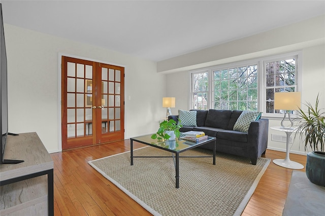 living area with french doors, visible vents, baseboards, and wood finished floors