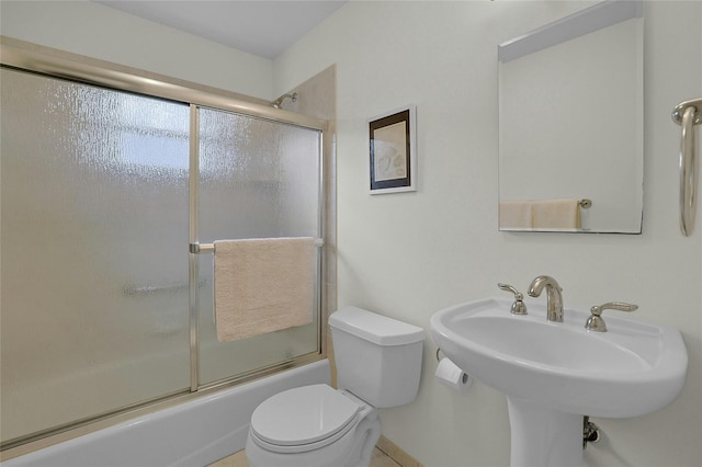 bathroom featuring toilet, enclosed tub / shower combo, and a sink