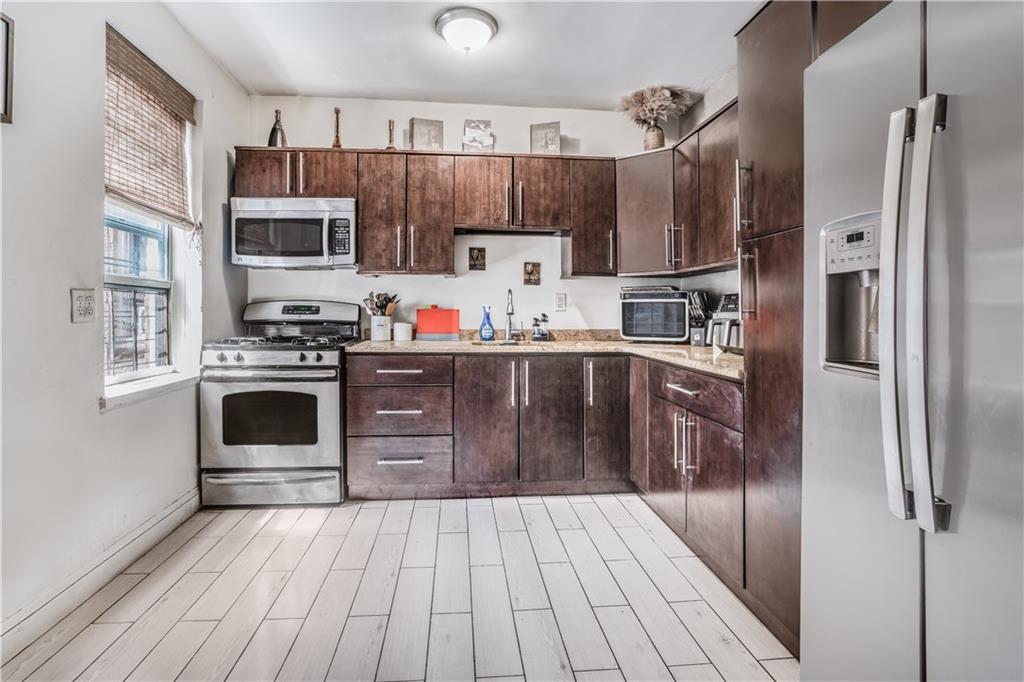 kitchen featuring light countertops, appliances with stainless steel finishes, a sink, and dark brown cabinets