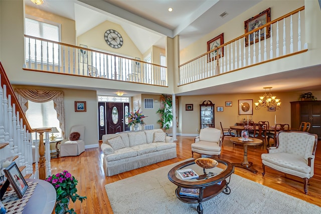 living room with visible vents, baseboards, a high ceiling, light wood-style floors, and a chandelier