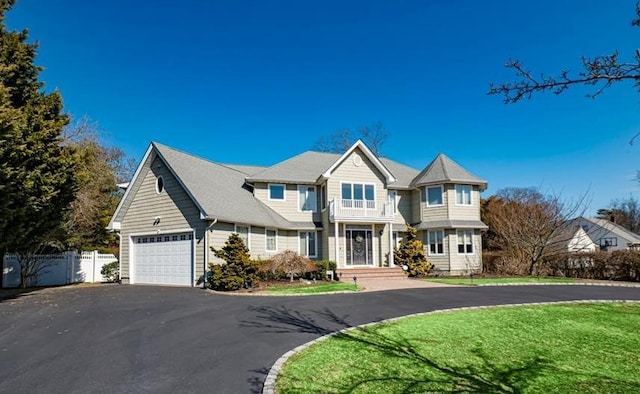 view of front of property featuring driveway, a front yard, fence, and a balcony