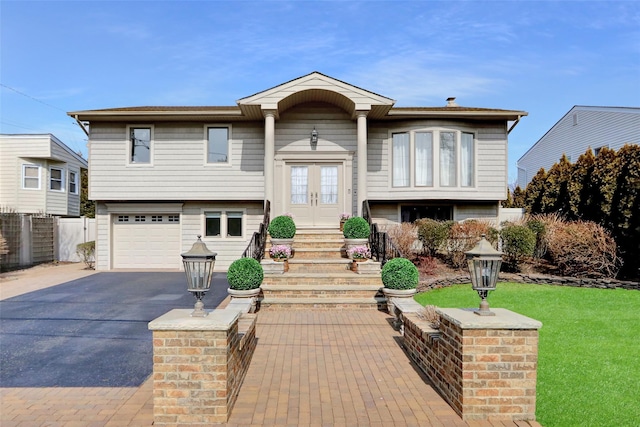 split foyer home with aphalt driveway, french doors, an attached garage, fence, and a front lawn