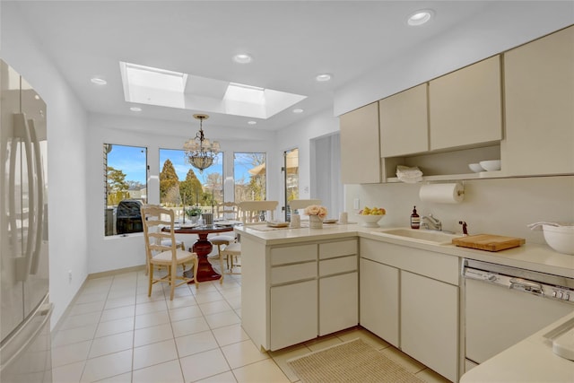 kitchen featuring refrigerator, a skylight, cream cabinets, dishwasher, and a peninsula