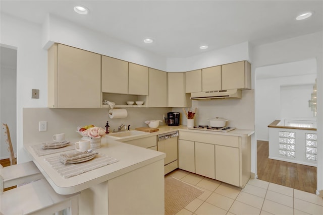 kitchen featuring white appliances, cream cabinets, a sink, and under cabinet range hood