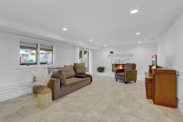 living room featuring a brick fireplace, light tile patterned floors, a decorative wall, and recessed lighting