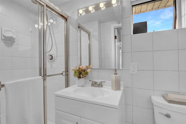 bathroom with toilet, a shower stall, tile walls, and vanity