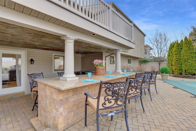 view of patio / terrace with a balcony, fence, and outdoor dry bar