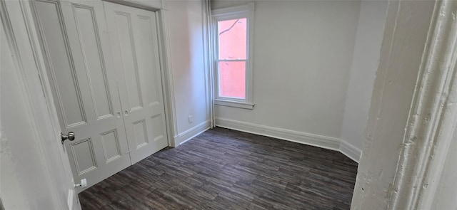 unfurnished bedroom with dark wood-type flooring and baseboards