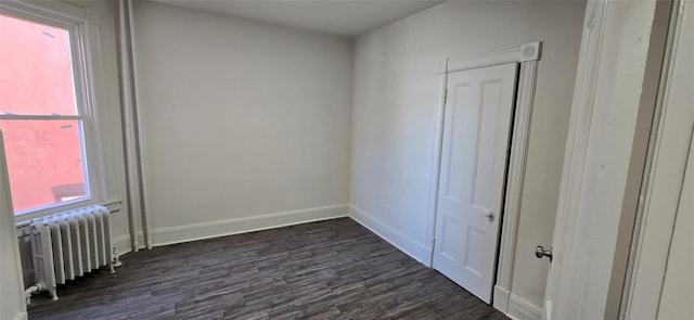 empty room featuring radiator, baseboards, and dark wood finished floors