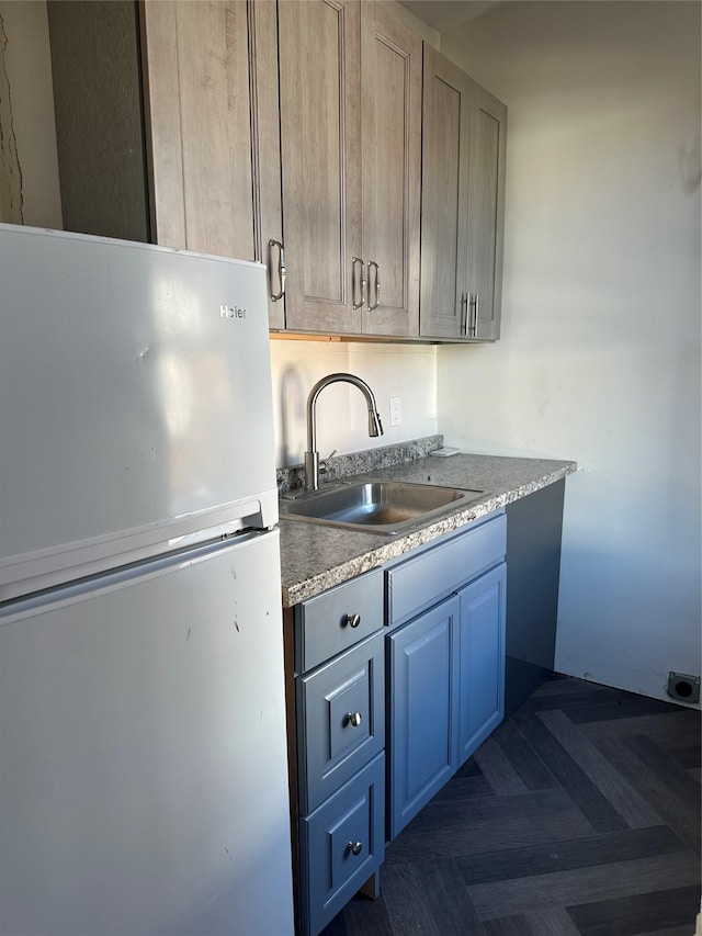 kitchen with freestanding refrigerator, light countertops, and a sink