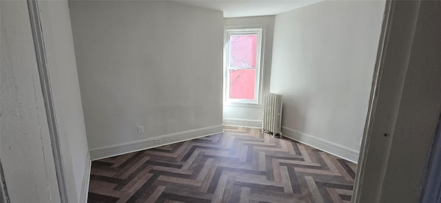 empty room featuring radiator and baseboards