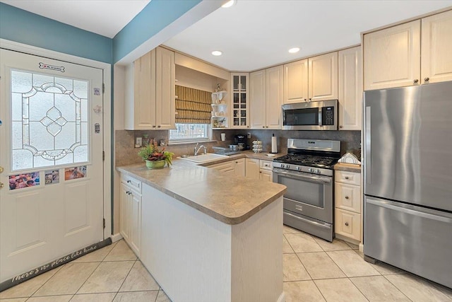 kitchen featuring a peninsula, light tile patterned floors, stainless steel appliances, and a sink