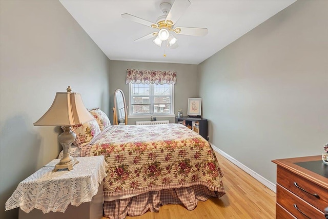 bedroom with light wood-type flooring, a ceiling fan, and baseboards