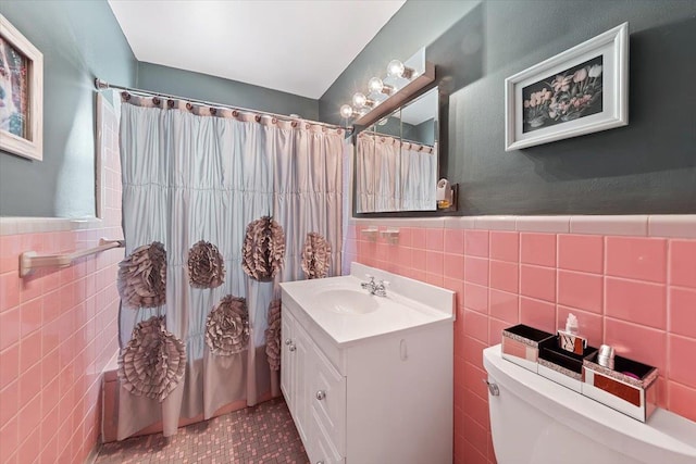 bathroom featuring toilet, a wainscoted wall, tile walls, and vanity