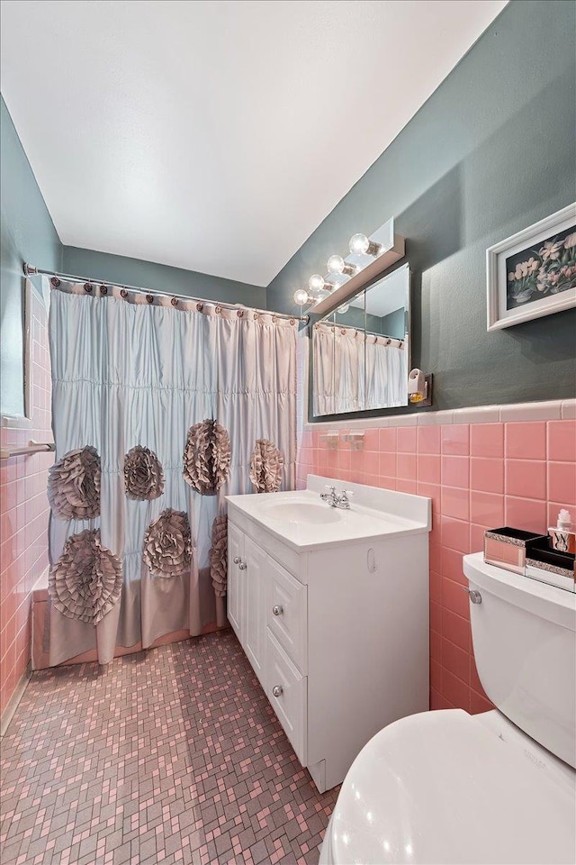 full bath featuring tile walls, toilet, wainscoting, vanity, and a shower with curtain