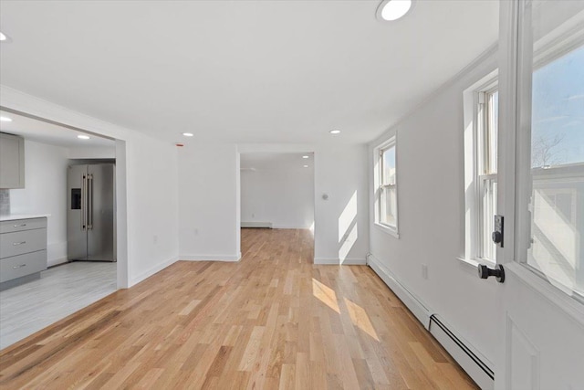 unfurnished living room featuring light wood finished floors, baseboards, baseboard heating, a baseboard heating unit, and recessed lighting