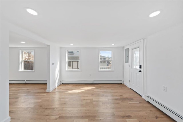 foyer entrance featuring a baseboard heating unit, a healthy amount of sunlight, and light wood-style floors