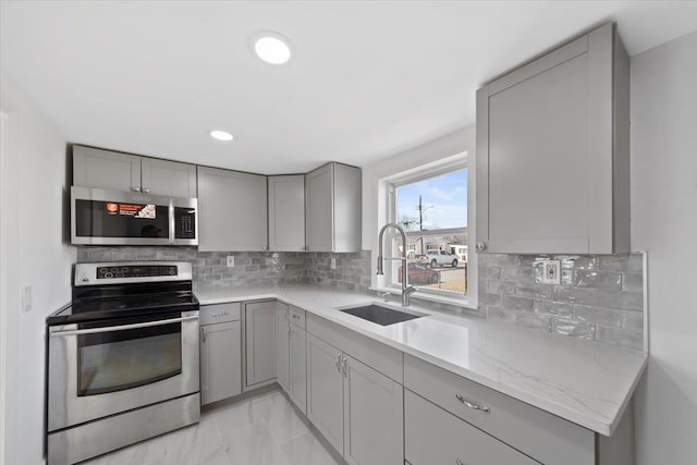 kitchen featuring marble finish floor, stainless steel appliances, a sink, and gray cabinetry