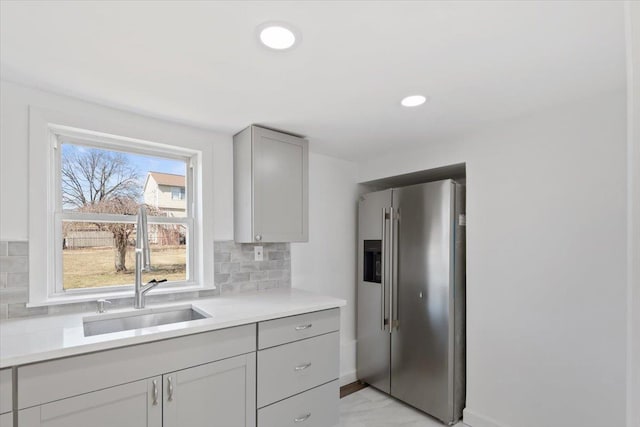 kitchen featuring a sink, marble finish floor, high end fridge, light countertops, and decorative backsplash