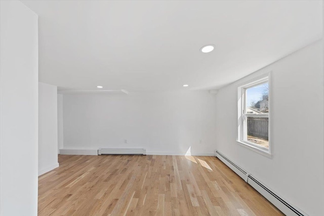 empty room with light wood finished floors, a baseboard radiator, recessed lighting, baseboard heating, and baseboards