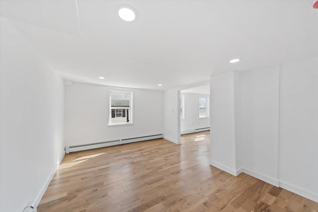 empty room featuring light wood finished floors, baseboards, baseboard heating, and recessed lighting