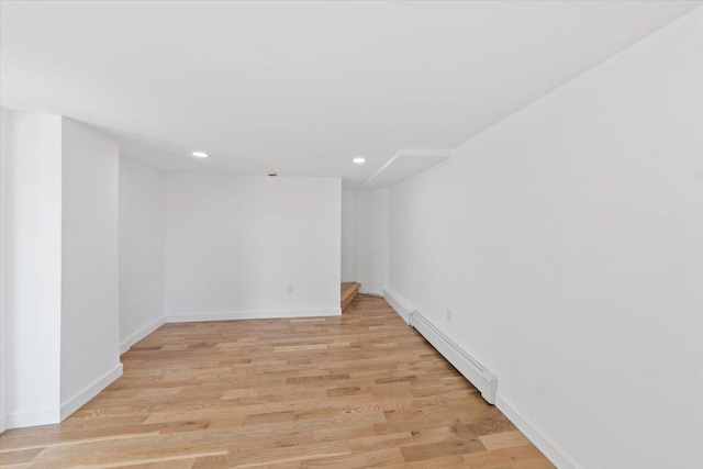 empty room with baseboards, recessed lighting, a baseboard radiator, and light wood-style floors