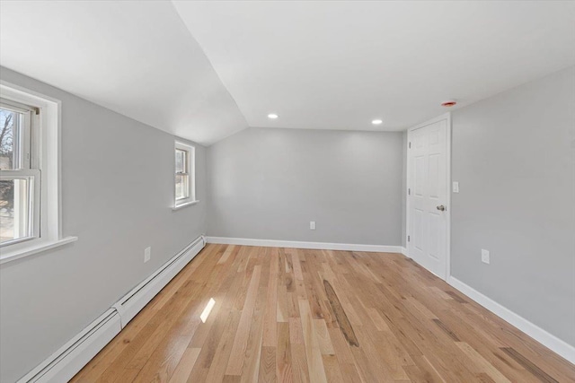 spare room featuring recessed lighting, a baseboard heating unit, baseboards, vaulted ceiling, and light wood-style floors