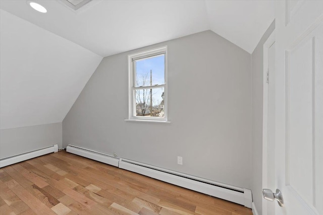 bonus room featuring light wood-type flooring, a baseboard radiator, baseboard heating, and vaulted ceiling