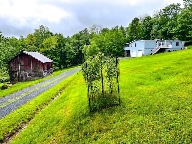521 Hessinger Lare Rd, Jeffersonville, NY 12748 - view of green lawn with a barn, an attached garage, an outdoor structure, a forest view, and driveway