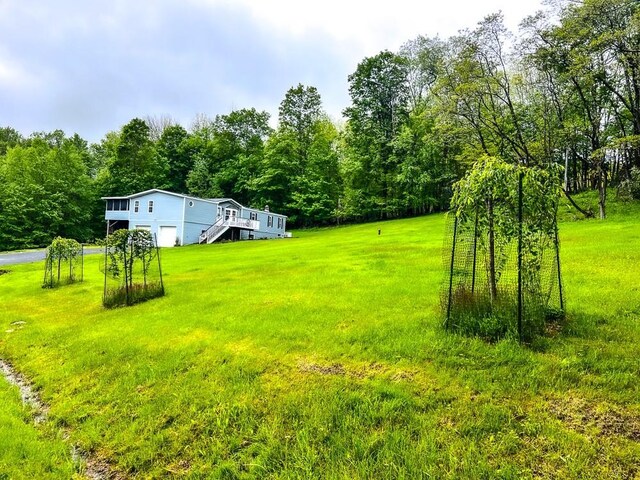 521 Hessinger Lare Rd, Jeffersonville, NY 12748 - view of grassy yard featuring a garage, a deck, a view of trees, and stairway