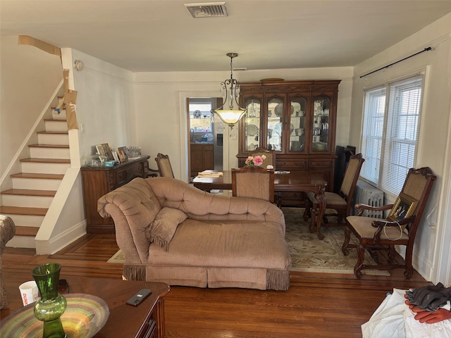 living area with stairs, visible vents, and wood finished floors