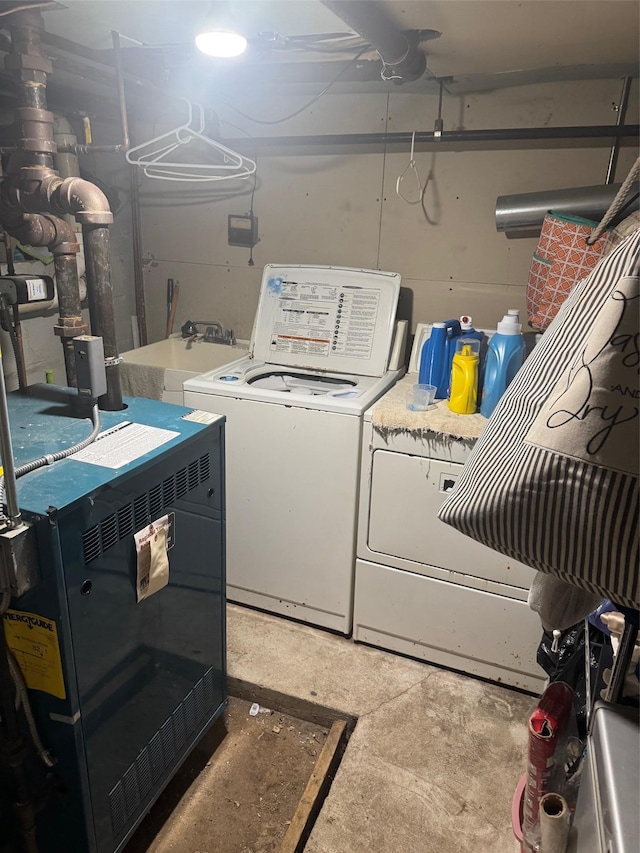 laundry area with laundry area, a heating unit, separate washer and dryer, and a sink