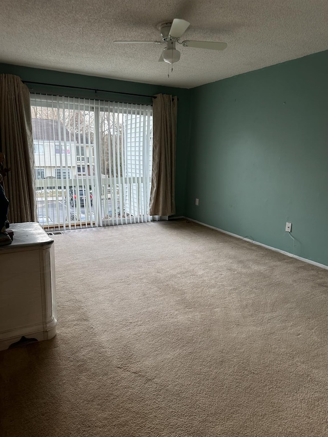 carpeted empty room with ceiling fan, a textured ceiling, and baseboards