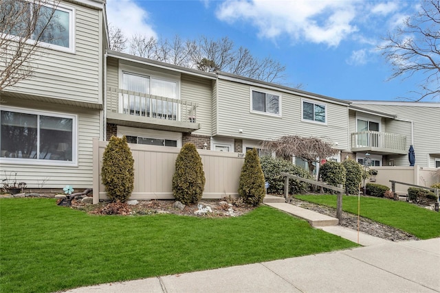 exterior space featuring a front lawn, fence, and brick siding