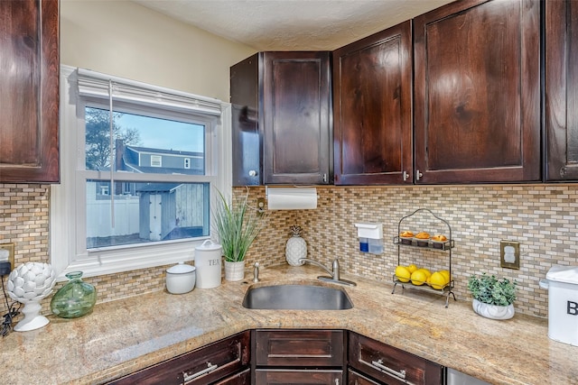 kitchen with dark brown cabinets, a sink, and decorative backsplash