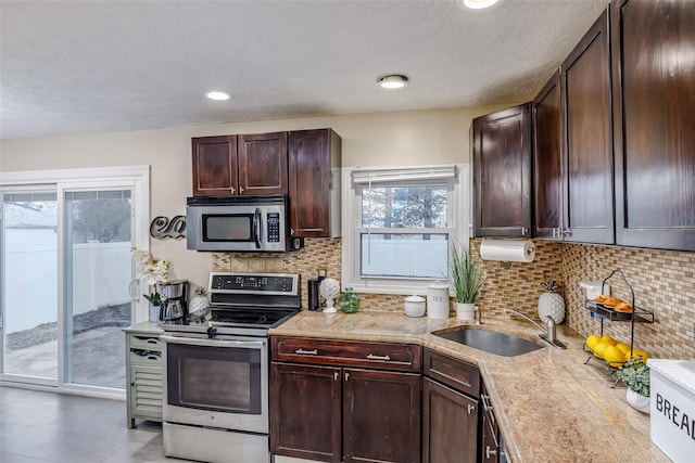 kitchen featuring dark brown cabinets, appliances with stainless steel finishes, a sink, and tasteful backsplash