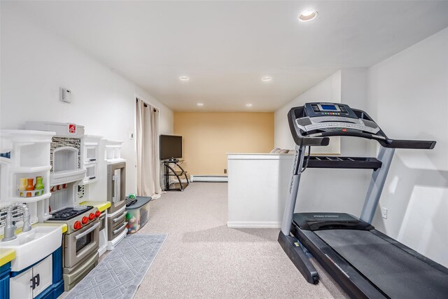 exercise room with a baseboard radiator, recessed lighting, light colored carpet, a sink, and baseboards