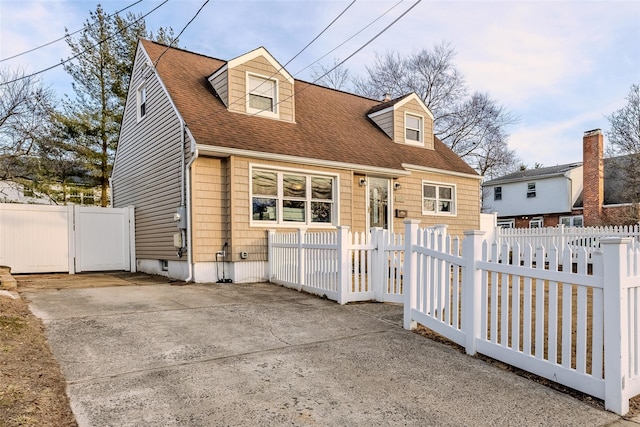 cape cod house featuring a fenced front yard, a gate, and a shingled roof