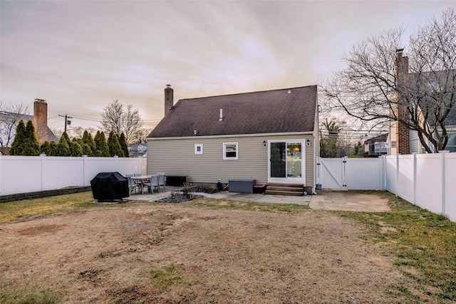 rear view of property with entry steps, a fenced backyard, a gate, a chimney, and a patio area