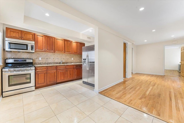 kitchen featuring light tile patterned floors, recessed lighting, stainless steel appliances, brown cabinets, and tasteful backsplash