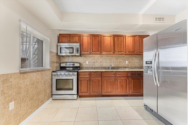 kitchen with light tile patterned floors, visible vents, appliances with stainless steel finishes, and brown cabinets